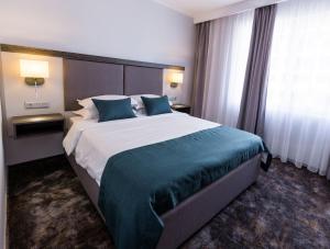 a hotel room with a large bed with blue pillows at Best Western PLUS Premium Inn in Sunny Beach
