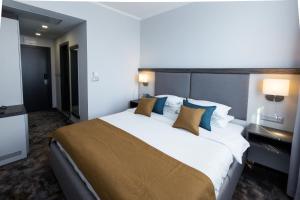 a hotel room with a large bed with blue pillows at Best Western PLUS Premium Inn in Sunny Beach