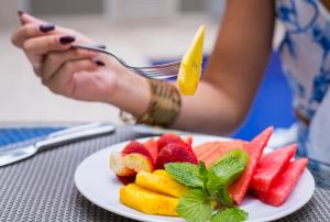 een vrouw die een stuk fruit op een bord eet bij Varanasi Hotel Boutique Aeropuerto in Cartagena