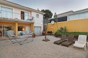 een achtertuin met een hangmat en stoelen en een huis bij Natalie Guesthouse in Bloubergstrand