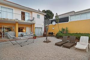 a backyard with a hammock and chairs and a house at Natalie Guesthouse in Bloubergstrand