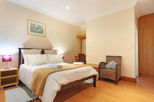 a bedroom with a large bed and a chair at Natalie Guesthouse in Bloubergstrand +25 photos