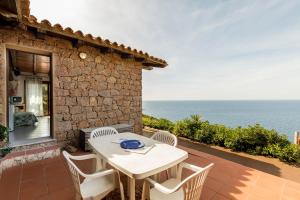 uma mesa branca e cadeiras num pátio com o oceano em Villa La Macchia em Costa Paradiso