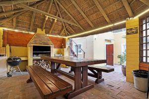 a large room with a wooden table and benches at Natalie Guesthouse in Bloubergstrand