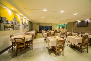 a restaurant with tables and chairs and a flat screen tv at Hotel Leiria in Matão