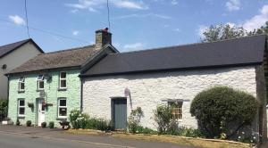 ein weißes und grünes Haus mit schwarzem Dach in der Unterkunft Brecon Boutique Breaks Wild Land in Sennybridge
