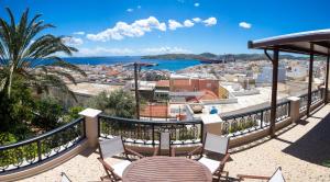 balcón con mesa, sillas y vistas a la ciudad en Villa Irene Syros en Ermúpoli