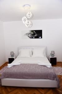 a white bedroom with a large white bed and a chandelier at Lux Apartman Casablanca in Plužine
