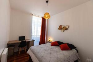 バイヨンヌにあるmagnifique appartement hypercentre toutes commoditésのベッドルーム1室(赤い枕のベッド1台、デスク付)
