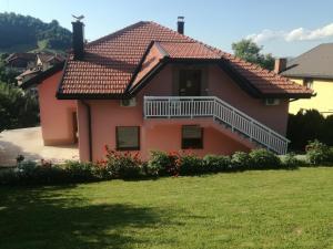 a pink house with a balcony and a yard at Edo in Visoko