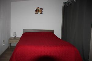 1 dormitorio con cama roja y edredón rojo en chez Pauline, en Fontès