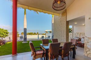een patio met een tafel en stoelen en uitzicht op de oceaan bij Villa La Caleta Golf in Adeje