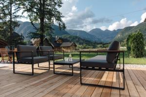 eine Terrasse mit 2 Stühlen und einem Tisch auf einer Holzterrasse in der Unterkunft Hotel Majerca in Bohinj