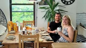 un hombre y una mujer sentados en una mesa con un celular en The Old Rectory, en Amlwch