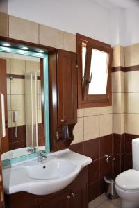 uma casa de banho com um lavatório, um WC e um espelho. em Melidron Hotel em Skála Kefalonias