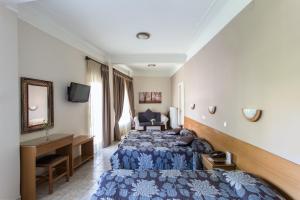 a hotel room with two beds and a desk at Anesis Hotel in Kozani