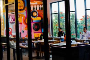 two people sitting at tables in a restaurant at Front One Hotel Tulungagung in Tulungagung