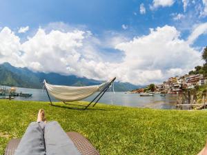 a person laying in a hammock next to a lake at NEW YORK by luxury atitlan in San Pedro La Laguna