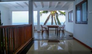 a dining room with a table and chairs and a palm tree at Hansa Surf Hotel in Hikkaduwa