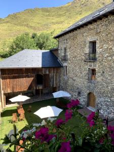 a building with umbrellas and tables and chairs and flowers at Ca Don Rafel in Castanesa