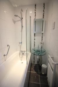 ein Badezimmer mit einer Badewanne und einem Glaswaschbecken in der Unterkunft Seafield House in Brighton & Hove