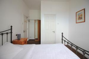 a bedroom with a white bed and a wooden table at Seafield House in Brighton & Hove