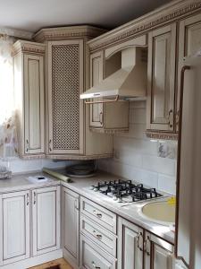 a kitchen with white cabinets and a stove and a sink at Sadyba Medova nasoloda in Guta