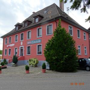 ein rotes Gebäude mit einem Baum davor in der Unterkunft Hotel Einstein in Bad Krozingen