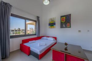 1 dormitorio con cama roja y ventana en Golden Apartments Pool View 1-Bedroom Apartment in G-Cribs, El Gouna, en Hurghada