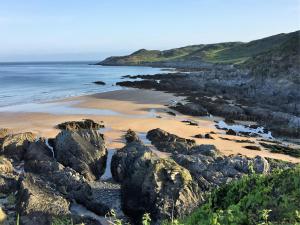 a sandy beach with rocks and the ocean at Watersmeet Hotel in Woolacombe
