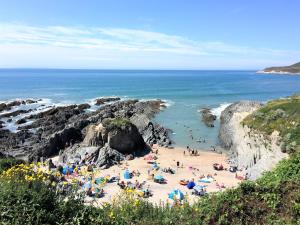 
a beach with people sitting on the sand at Watersmeet Hotel in Woolacombe
