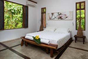 um quarto com uma cama com toalhas e 2 janelas em Pousada da Amendoeira em São Miguel dos Milagres