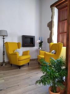 uma sala de estar com duas cadeiras amarelas e uma televisão em La Casita de Ainhoa em Agüimes