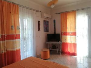 a bedroom with curtains and a tv and a bed at Paliorouga Lodge Zakynthos in Langadhákia