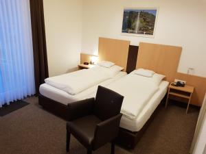 a hotel room with two beds and a chair at Hotel zum Anker in Andernach