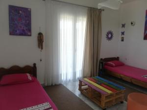 sala de estar con 2 camas y ventana en Paliorouga Lodge Zakynthos, en Langadhákia