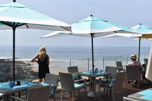 a woman standing on a patio with tables and umbrellas at Watersmeet Hotel in Woolacombe