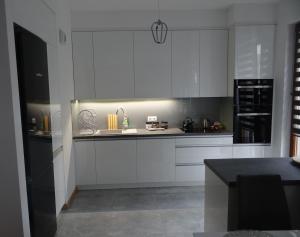 クラクフにあるBeautiful City Centre Apartamentのキッチン(白いキャビネット、黒いカウンタートップ付)