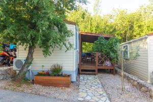 a tiny house with a porch and a tree at Krk Mobile Homes in Klimno