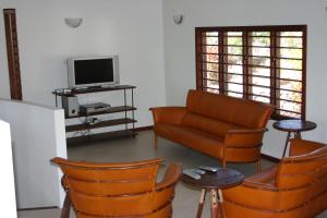 a living room with a couch and chairs and a tv at Bularangi Villa, Fiji in Rakiraki
