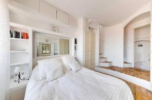 a white bedroom with a large bed with white walls at Ciel d´Azur in Roquebrune-Cap-Martin