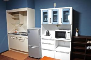 una pequeña cocina con nevera y microondas en Yokocho Building / Vacation STAY 42628, en Beppu