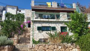 a building with a balcony and stairs with flowers at Apartments Vila Vino in Sveta Nedelja