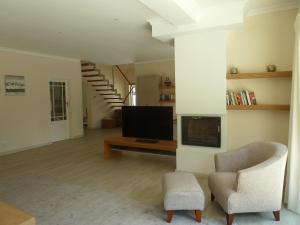 Una sala de estar con un televisor y una silla. en Villa Karibu, en Tokai