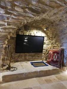 uma sala de estar com televisão numa parede de pedra em בבית של סבתא וסבא em Safed