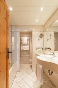 a bathroom with a sink, toilet and shower at Hotel Europa St. Moritz in St. Moritz
