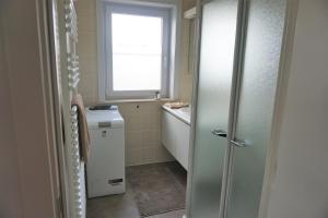 a bathroom with a shower and a sink and a window at Den Oever in Middelkerke