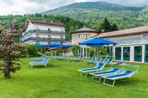 un grupo de tumbonas y sombrillas azules en un patio en Hotel Al Sorriso Greenpark & Wellness en Levico Terme