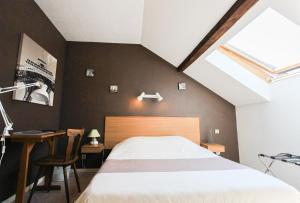 a bedroom with a bed and a desk and a window at Hotel Restaurant De La Poste Mulhouse Ottmarsheim in Bantzenheim