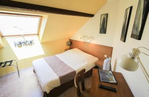 a bedroom with a bed and a table with a lamp at Hotel Restaurant De La Poste Mulhouse Ottmarsheim in Bantzenheim